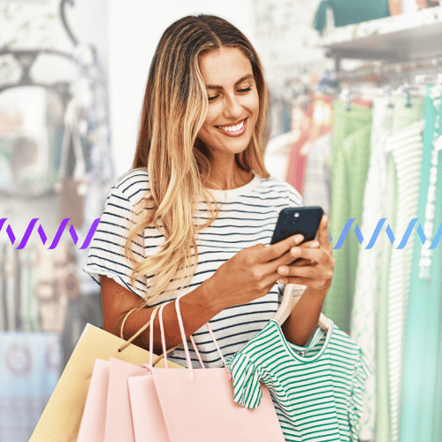 Photo of a smiling customer shopping for clothes in a store. She is looking at her phone and texting. In the background, a series of purple-to-blue wave forms runs across the frame.