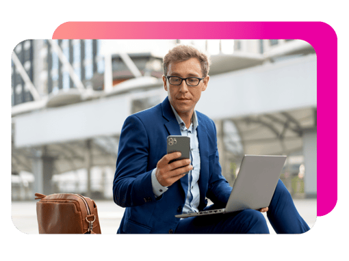 Image of a man sitting outdoors with a laptop and phone