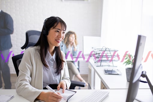 A customer service agent taking notes in front of a computer