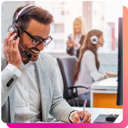 Male call center agent smiling while talking on a headset while wielding a pen