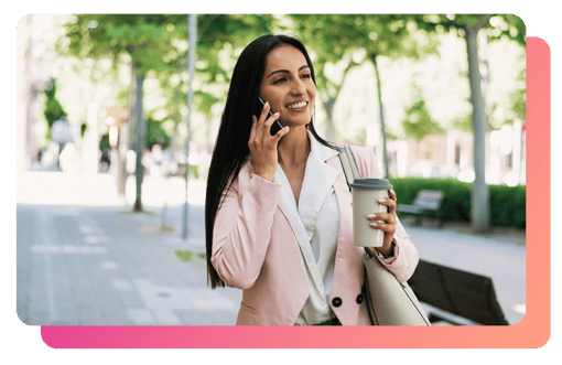 Young professional woman smiling while using her Vonage Mobile plan to talk on her cellular device Young business woman smiling while on phone while holding a cup of coffee outside
