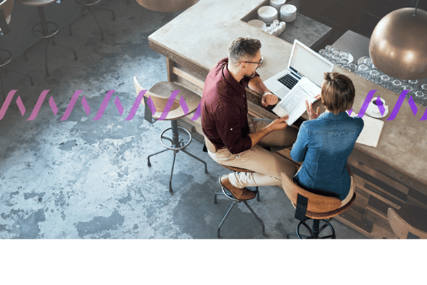 Vonage around the world Image of two workers sitting on stools at a counter with a laptop, reviewing paperwork