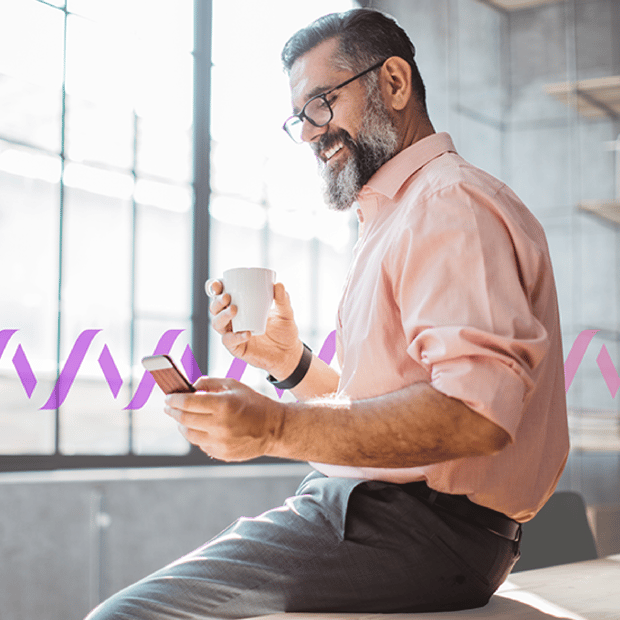 Photo of a smiling bearded man in an office, talking to someone and texting on his mobile phone. In the background, a series of purple wave forms run across the frame.