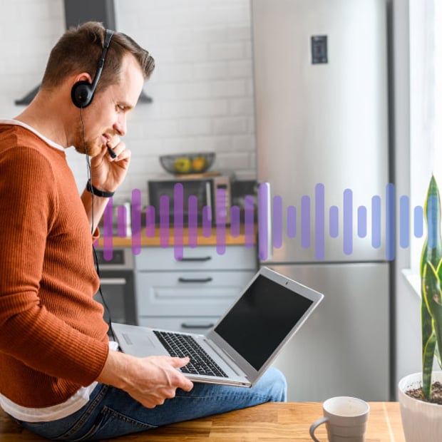 UC SEO Hosted VoIP Blog Header Photo of a casually dressed employee sitting on his desk working on his computer and talking into a headset.