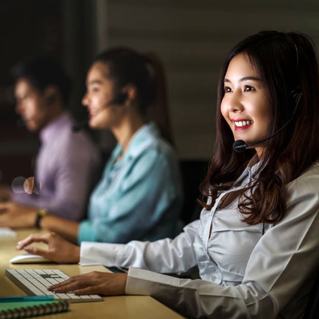 Photo of several employees with telephone headsets speaking with customers or other employees