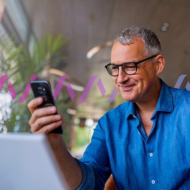 UC What Is PBX Blog Header Photo of a smiling man looking at something on his cell phone screen