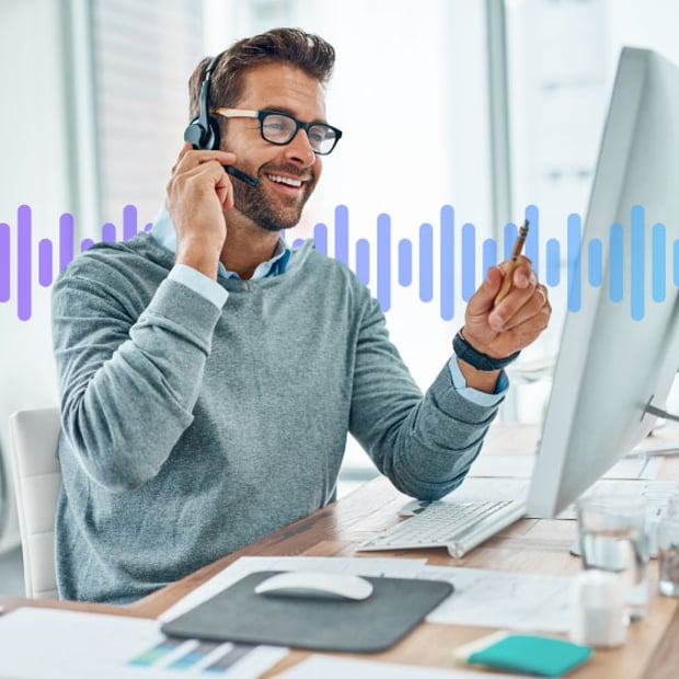 Image of man wearing a headset, talking on the phone, and looking at a computer screen