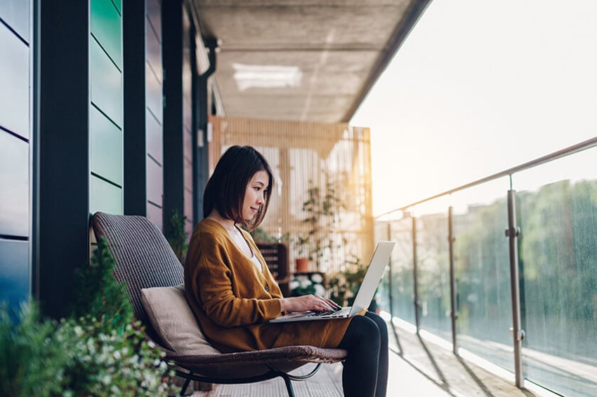 woman doing remote work on laptop on balcony