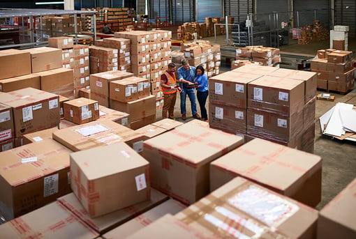 three people talking in middle of warehouse filled with boxes